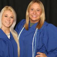 two friends with hands on hips smiling